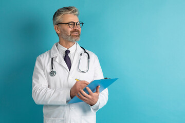 Handsome middle aged doctor taking anamnesis, blue background