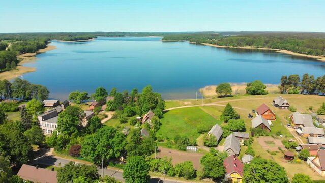 Lusiai lake panorama aerial view with cars on road drive pass vintage houses in Paluse village - famous travel destination in Lithuania, Baltics, Europe