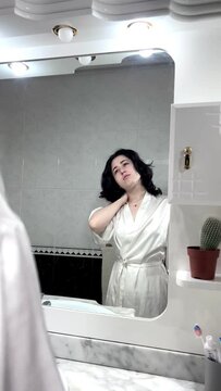 video of portrait of a latin woman with neck and back pain in front of the mirror. sleeping in bad postures or working in bad conditions can cause excessive neck pain