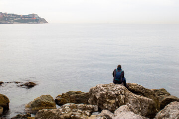 Fototapeta na wymiar Person sitting by the sea watching the sea