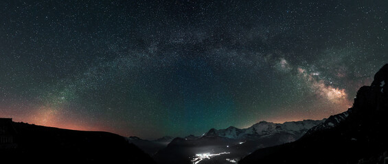 Milky Way arc and stars in night sky over the Swiss Alps with the famous alpen peaks Eiger, Monch...
