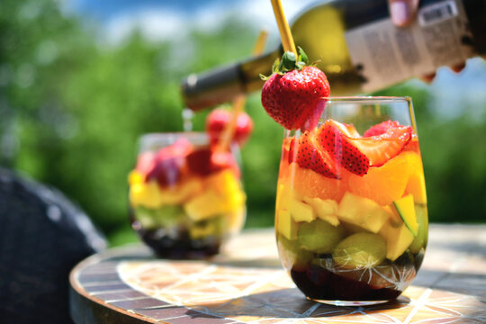 Glasses of colorful rainbow sangria, summer cocktail fruit alcohol drink outside.