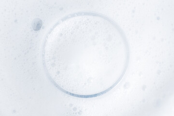 Washing agent foam in a Petri dish. On a blue background.