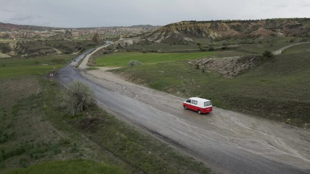 Aerial view of a small camper van crossing the Love Valley in Goreme National Park, Goreme, Cappadocia, Nevsehir, Turkey.