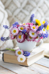 Greeting postcard with bright summer or spring flowers in a cute cup. Congratulations for Mother's or Women's day, birthday or anniversary. Countryside decor, old book, wooden background, straw hat
