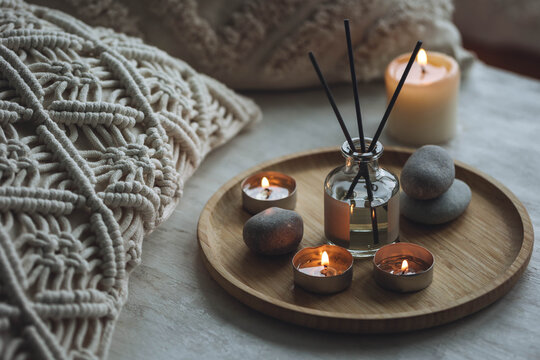 Apartment natural aroma diffusor with sea breeze fragrance. Burning candles on bamboo tray, cozy home atmosphere. Relaxation, detention zone in the living or bedroom. Stones as decor