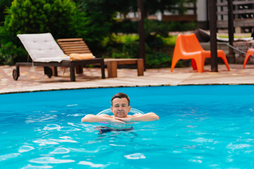 Naklejka premium Portrait of a cheerful middle-aged man in the pool with inflatable lifebuoy.