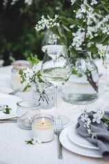 Romantic elegant luxury wedding table decor with white fresh spring blooming cherry apple tree flowers. Glass, candles, floral decoration for special marriage holiday event. No plastic zero waste