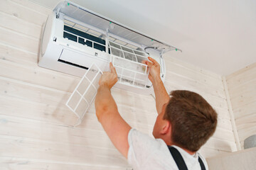 A man replaces and cleans the air cleaner filter from the air conditioner.