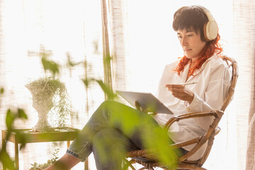 woman using tablet to draw working at home in a quiet space while having a video call red-haired woman smiling, with a bird next to the woman