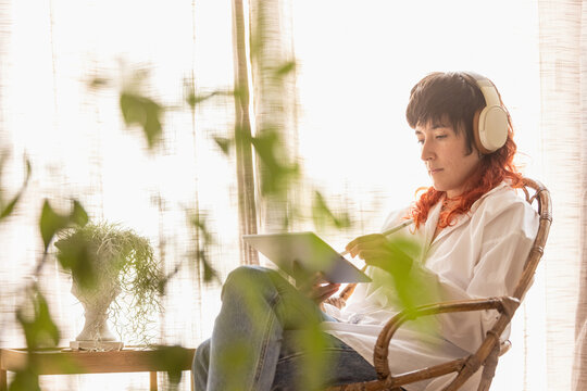 woman using tablet to draw working at home in a quiet space while having a video call red-haired woman smiling, with a bird next to the woman - Powered by Adobe
