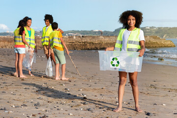 Glad different teenager children volunteers in vests collect garbage, black girl carries box for recycling