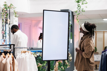 African american customer using smart board with empty screen to check information shoes collection in shopping mall. Man examining promotion on whiteboard in department store