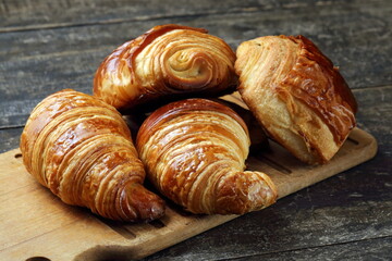 Traditional croissant and croissant au chocolat on wooden cutting board