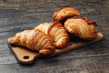 Traditional croissant and croissant au chocolat on wooden cutting board