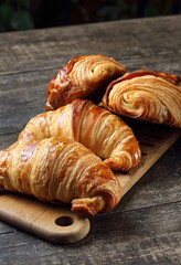 Traditional croissant and croissant au chocolat on wooden cutting board