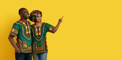Loving black lovers pointing at copy space on yellow