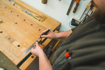 Hands of carpenter carefully drawing line using marker and ruler on wooden plank. High quality photo