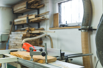 Wooden plank with rough edges placed next to a table saw in a carpenter workshop. High quality photo