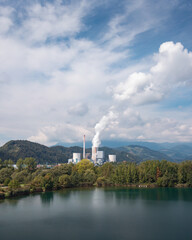 Smoking chimney at thermal power plant near lake and green nature. Aerial view