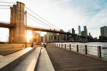 View of Brooklyn Bridge with Lower Manhattan in the background, lit by sunset
