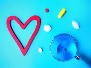 Stethoscope and pills next to a Red heart. Heart health concept