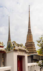 Fototapeta premium Golden spires and part of the facade raising against the sky at the Wat Pho temple in Bangkok, Thailand.