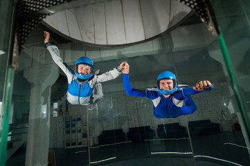 Obraz na płótnie Canvas A man and a woman enjoy flying together in a wind tunnel. Free fall simulator