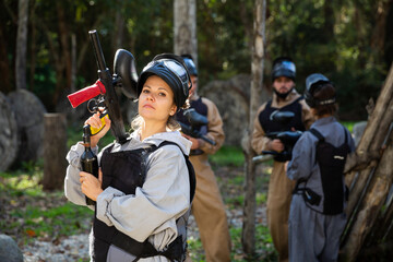 Fototapeta premium Woman and her paintball sport team in protective uniform at shooting range