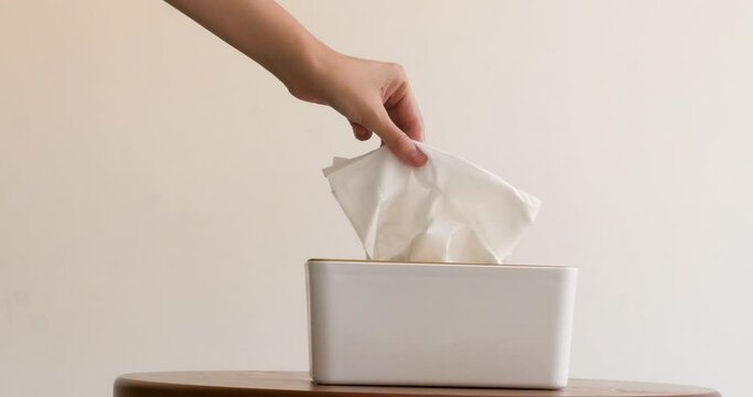 Woman taking tissue from box on wooden table white background close up