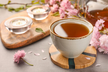 Obraz na płótnie Canvas Traditional ceremony. Cup of brewed tea, teapot and sakura flowers on grey table, closeup