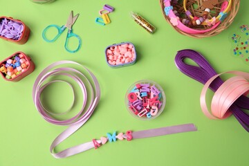 Fototapeta Handmade jewelry kit for children. Colorful beads, ribbons and supplies on green background, flat lay obraz