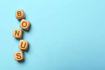 Word Bonus made of color cubes with letters on light blue background, top view. Space for text