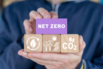 Man holding colorful blocks with icons and inscription: NET ZERO. Carbon Neutral and Net Zero...