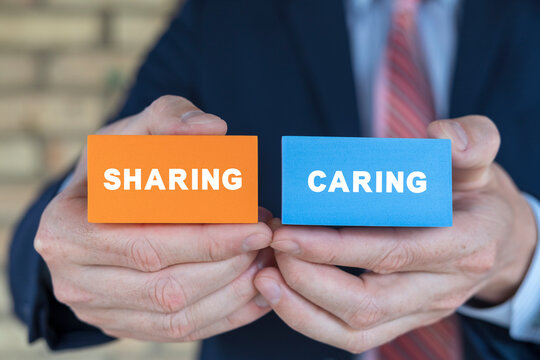 Businessman holding colorful styrofoam blocks with text: SHARING CARING. Concept of sharing caring. Business, sharing is caring concept. - Powered by Adobe