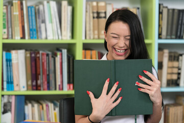 Happy Female Student Reading from Book in Library