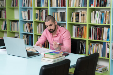 Happy Male Student With Laptop in Library