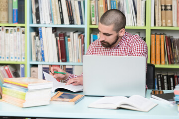 Young Student Using His Laptop In A Library