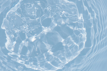 Blue water with ripples on the surface. Defocus blurred transparent blue colored clear calm water surface texture with splashes and bubbles. Water waves with shining pattern texture background.
