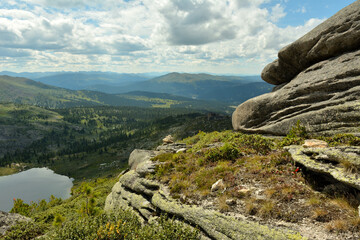 Layered basalt monolith on top of a mountain overlooking a picturesque valley in the mountains with a beautiful lake.