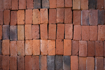 A symmetrical background of red bricks stacked on a construction site.