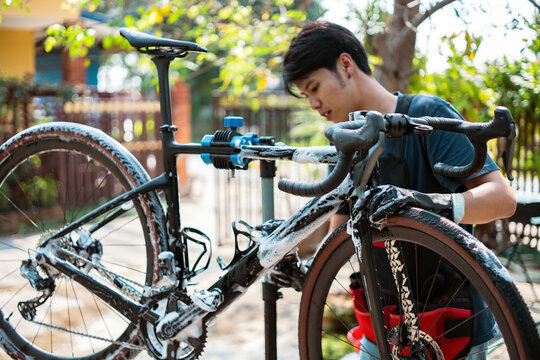 Asian bike mechanic washing a customer's bike.