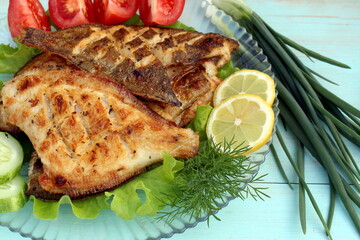 Grilled flounder fish with vegetables is on the plate.