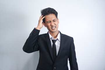 Handsome asian young man wearing suit over isolated background suffering from headache of despair and stress due to illness and migraine. Hands on head.