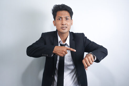 Handsome Asian Young Man Wearing Suit Standing On Isolated White Background In A Hurry Pointing To Watch Time, Impatient, Annoyed And Angry Because Of Delayed Deadline