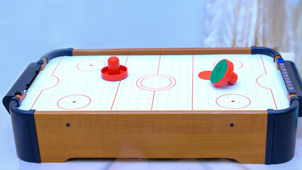 The plot shot of an air hockey game on a table Portable table hockey includes plastic hockey blades, a mini puck and goalkeepers