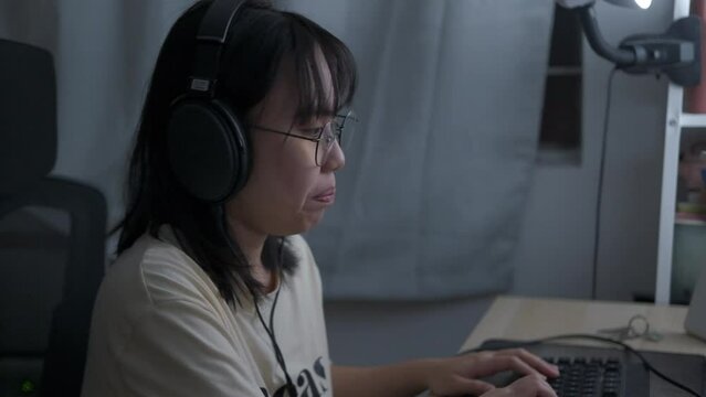 Southeast Asian Filipino woman yawns and puts headphones up on desk after coding for work