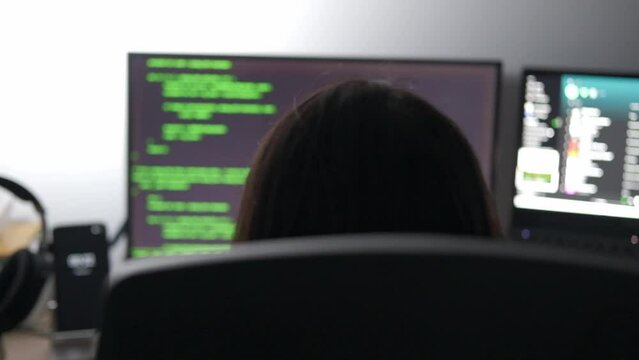 Woman coding cybersecurity in python places headphones on stand and leaves desk