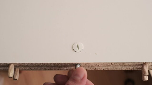 The furniture assembler assemble the interior furniture, close fixer sby screw and fixers, hands with a close-up