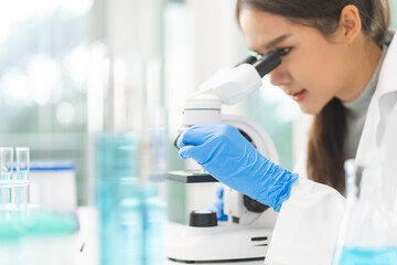 Medical development research laboratory, science young woman scientist hand in glove looking under microscope for test analysis samples in lab. Microbiology, analysing biochemicals for medicine.